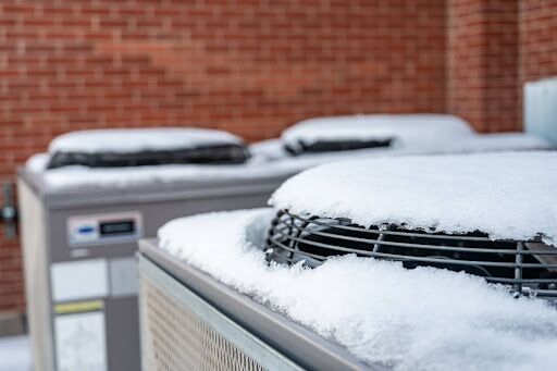 A snow-covered outdoor AC unit